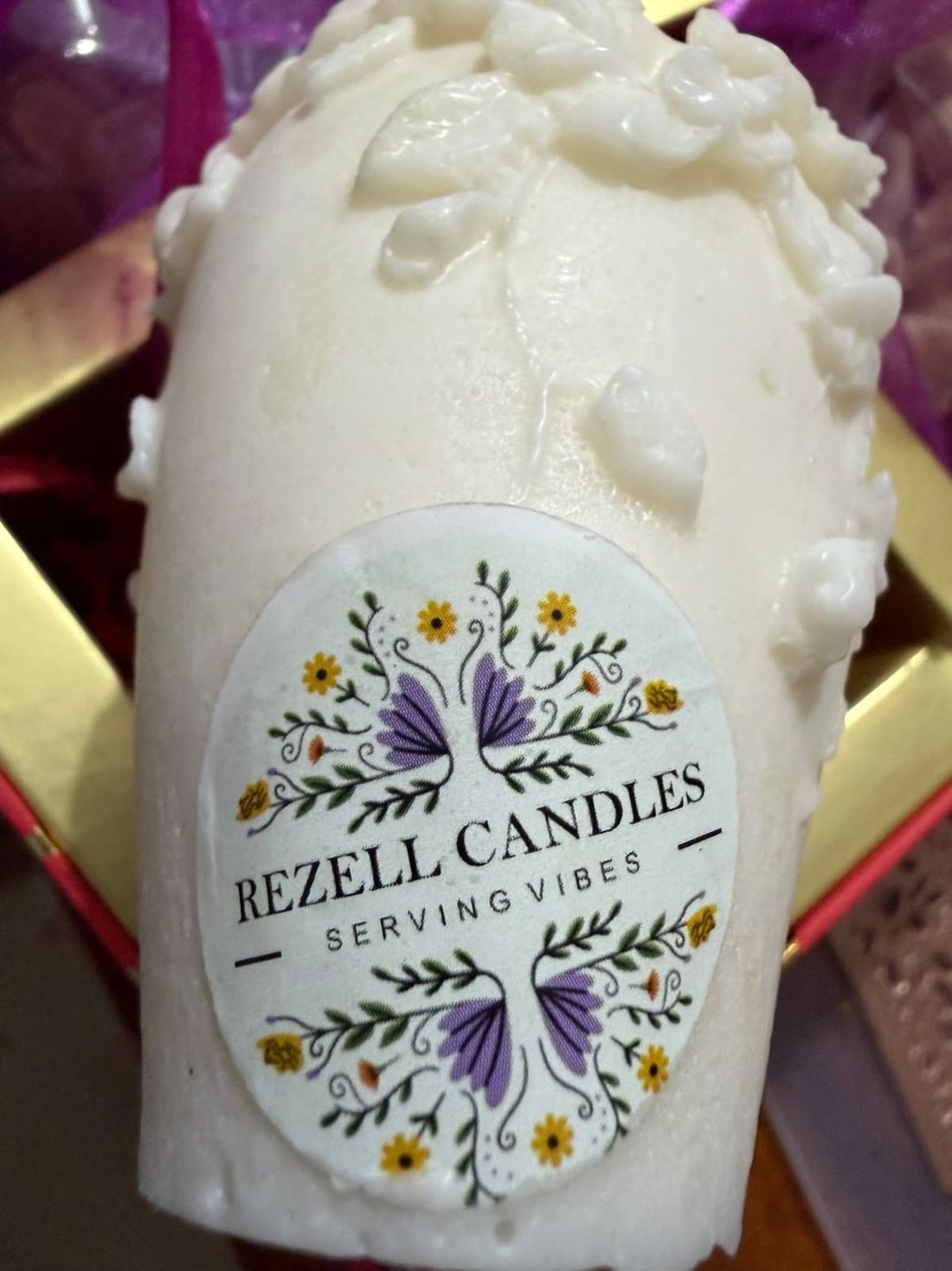Rezell Candles label on a floral ivory candle