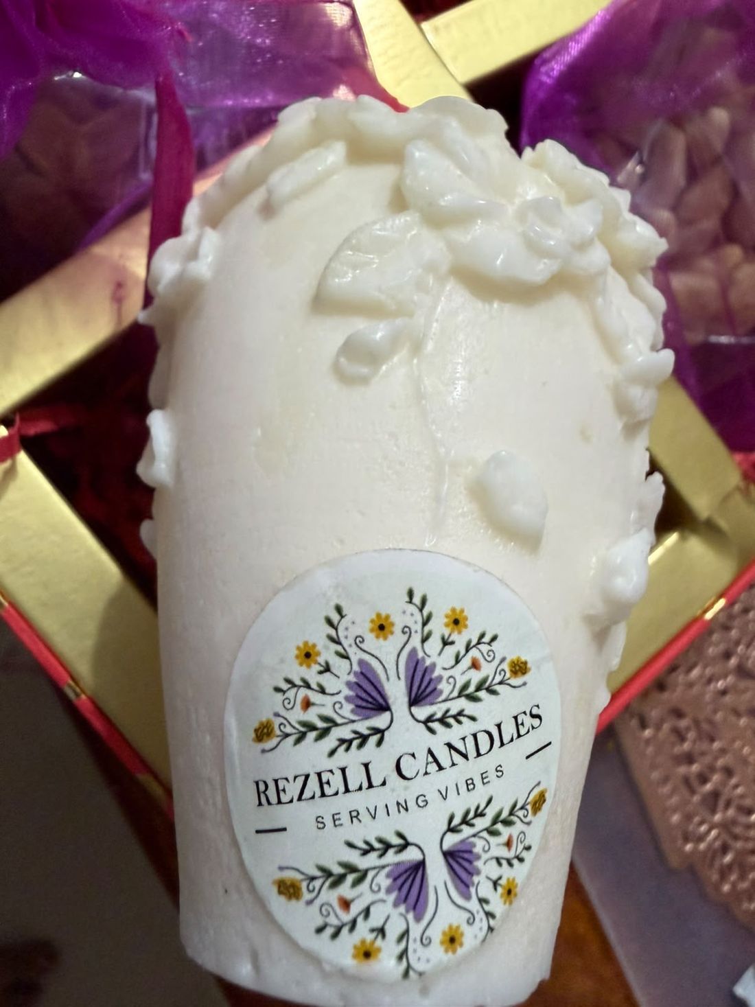 Rezell Candles label on an ivory floral candle